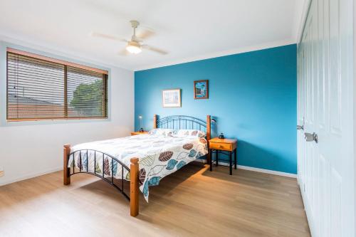um quarto com uma cama e uma parede azul em Clifton on Charles em Iluka