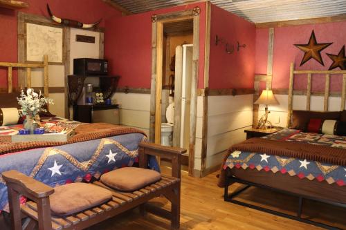 2 łóżka w pokoju z czerwonymi ścianami w obiekcie Acorn Hideaways Canton Cozy Frontier Suite 1890s Cattle & Land Decor w mieście Canton