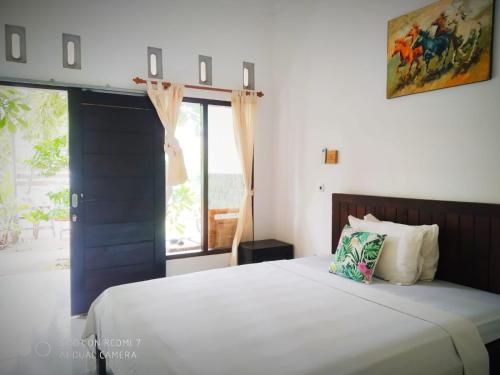 a bedroom with a large white bed with a window at Ping Pong homestay Gili Trawangan in Gili Trawangan