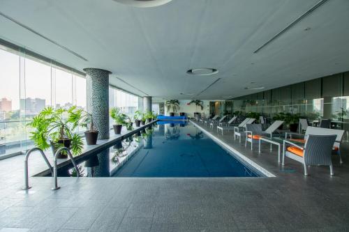 a lobby with a pool with chairs and plants at Capitalia Plaza Residences Reforma in Mexico City