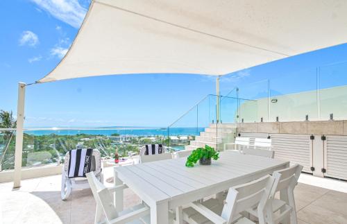 a white table and chairs on a balcony with a view of the ocean at Noosa Crest Penthouse 40 - Private Rooftop Pool in Noosa Heads