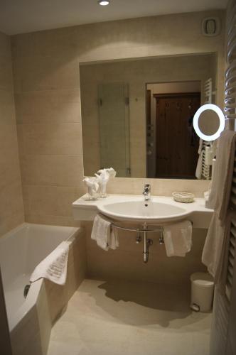 a bathroom with a sink and a tub and a mirror at Hotel Spielmann in Ehrwald