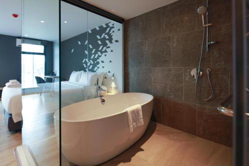 KOO HOTEL في Ban Bang Talat: حمام مع حوض استحمام وغرفة نوم