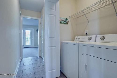 Una cocina blanca con lavadora y secadora. en Beautiful 4 bed 3 bath beach cottage with wonderful ocean views, en Surf City