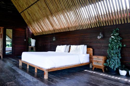 a bedroom with a large bed with a wooden wall at Let's Get Lost Ubud in Ubud