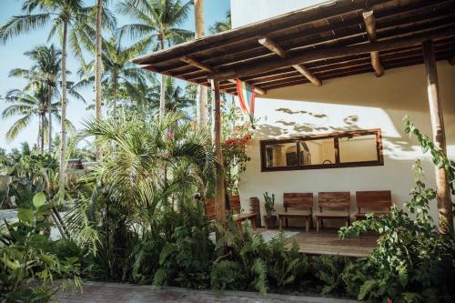 a house with a wooden porch with benches and palm trees at Vedya Boutique Hostel in General Luna