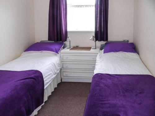 2 bedden in een slaapkamer met paarse lakens en een raam bij Seanicview Villa in Saint Martin