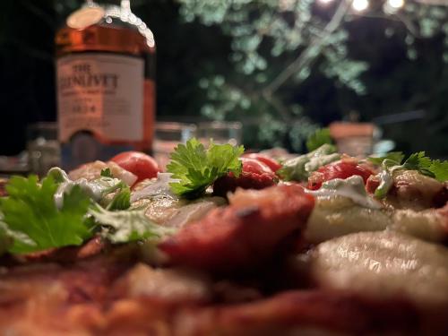 a close up of a pizza with tomatoes and greens on it at Ella Nine Peaks in Ella