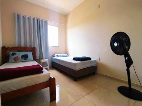 a bedroom with two beds and a fan in it at Casa Amarela na Praia de Guaibim-Taquari in Guaibim