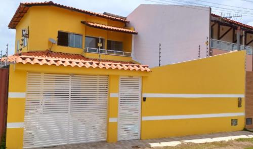 a yellow and white house with two garage doors at Casa Amarela na Praia de Guaibim-Taquari in Guaibim