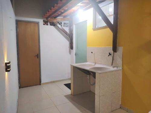 ein Bad mit einem Waschbecken neben einer Tür in der Unterkunft Casa Amarela na Praia de Guaibim-Taquari in Guaibim