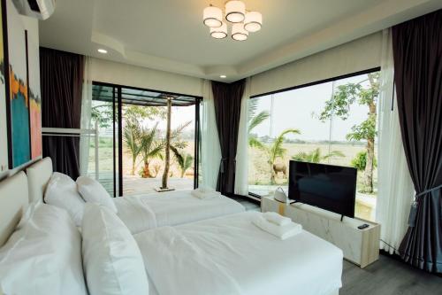 1 Schlafzimmer mit 2 weißen Betten und einem TV in der Unterkunft KEPT Cabana เคปท์ คาบานา in Lampang