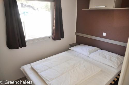 un petit lit dans une chambre avec une fenêtre dans l'établissement Greenchalets Camp Lei Suves, Roquebrune sur Argens ( Provence- Cote d'azur), à Roquebrune-sur Argens