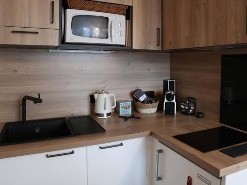 une cuisine avec un évier et un micro-ondes dans l'établissement Les Orres 1650: Studio confort 4 pers, navette, lave-linge - FR-1-322-516, aux Orres