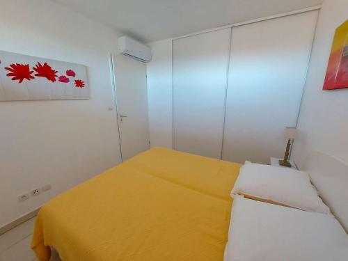 mały pokój z żółtym łóżkiem w obiekcie Appartement 2 pièces avec accès direct plage, piscine et terrasse - Marseillan - FR-1-326-778 w mieście Marseillan