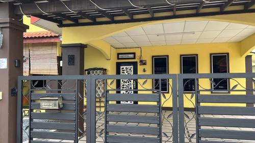 a yellow house with a gate and stairs in front at Homestay Rumah Cikgu 3bilik tidur in Jitra
