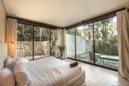 a bedroom with a bed and a large window at Tulum Retreat-3BR Luxury Condo-Private Pool in Tulum