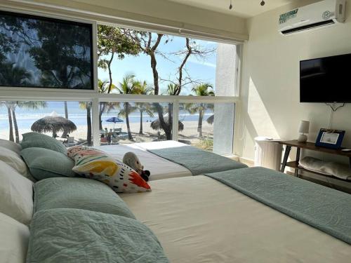 a bedroom with three beds with a view of the beach at Playa Caracol, beach happy in Chame