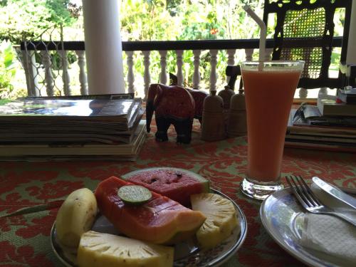 a plate of fruit on a table with a drink at Leijay Garden Retreat in Galle