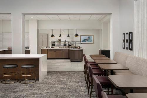 a restaurant with tables and chairs and a kitchen at Staybridge Suites San Antonio Airport by IHG in San Antonio