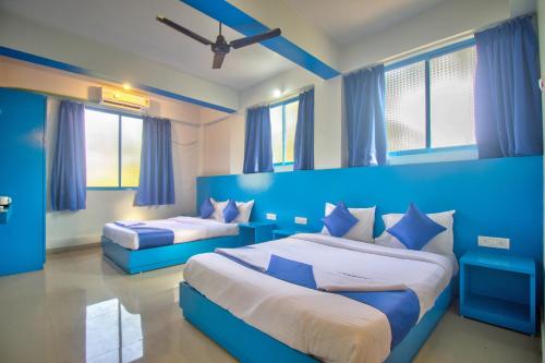 a blue bedroom with two beds and windows at Mandrem Retreat Beach resort in Mandrem