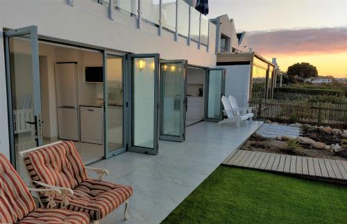 a patio with glass doors and two chairs on it at Soli Deo Gloria, Pearl Studio in Paternoster