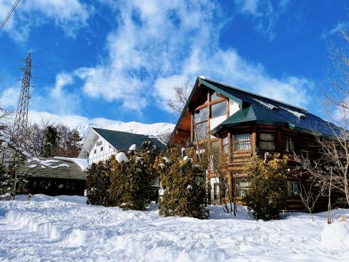 a log cabin in the snow with snow covered trees at Hakuba Pension & Log Hotel Meteor in Hakuba