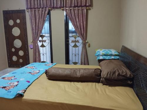 un letto con una coperta in una camera da letto di Mando Homestay II a Bukittinggi