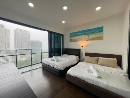 two beds in a room with a large window at Almas Suites Double Bed @Legoland in Nusajaya