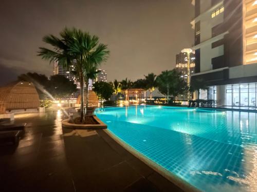 a large swimming pool with a palm tree next to a building at Almas Suites Double Bed @Legoland in Nusajaya
