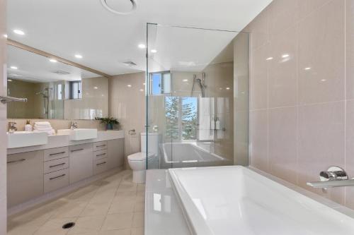 Un baño con bañera, inodoro y ducha. en The Garland at Rainbow Bay, en Gold Coast