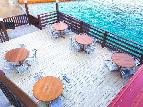 four tables and chairs on a deck next to the water at Perhentian Nemo Chalet in Perhentian Island