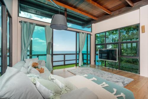 a person sitting on a couch in a living room with a television at Villa at Nai Harn Cape / Ocean Point in Nai Harn Beach