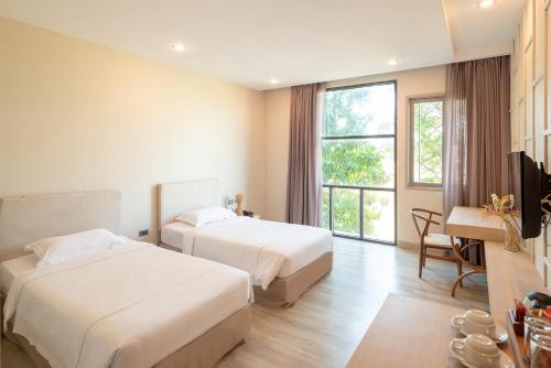 a hotel room with two beds and a television at Navela Hotel & Convention in Ratchaburi