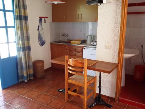 a small kitchen with a wooden table and a chair at S West Crete Cottage in Palaiochóra