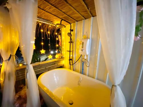 baño con bañera amarilla y ventana en ดูดาวแคมป์ริมโขง, en Chiang Khan