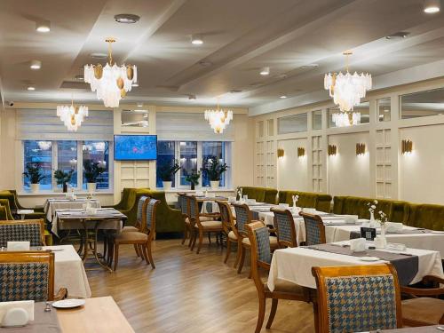 a dining room with tables and chairs and chandeliers at Hotel Dastan Aktobe in Aktobe