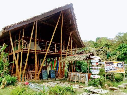 a house with a thatched roof and chairs in front of it at Surf and Skate Duli El Nido By Kiteclub Palawan in El Nido