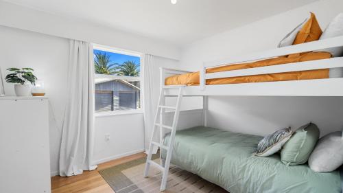 ein Schlafzimmer mit einem Etagenbett und einer Leiter in der Unterkunft The Links - Mount Maunganui Holiday Home in Mount Maunganui