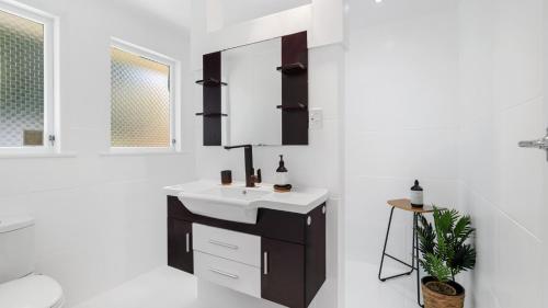 a bathroom with a sink and a mirror at The Links - Mount Maunganui Holiday Home in Mount Maunganui