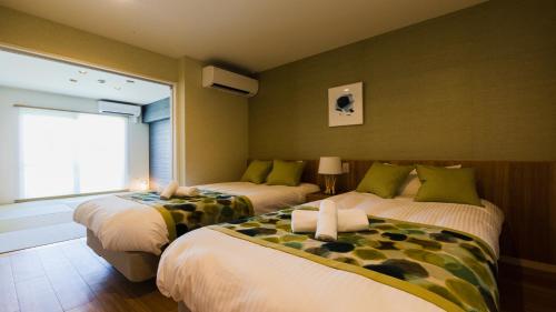 two beds in a room with a window at Alpha Terrace Onna Hills in Onna