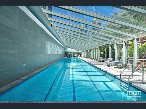 a large swimming pool with blue water in a building at RiverView Spacious 3BR2Bath2Car WifiPoolGym Crown in Melbourne