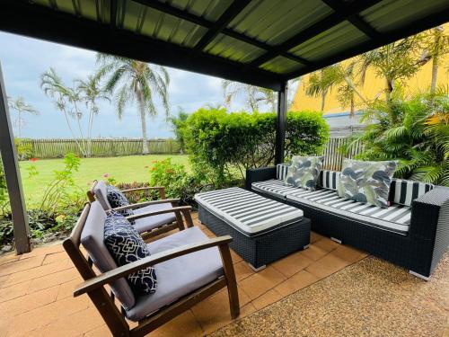 a patio with couches and chairs under an umbrella at 18 Knudsen Street in Elliott Heads