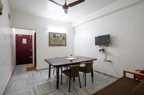 a dining room with a table and chairs and a tv at Sri Aarvee Hotels in Coimbatore