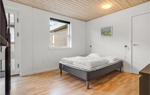 a bed in a white room with a wooden ceiling at Awesome Home In Ørsted in Ørsted