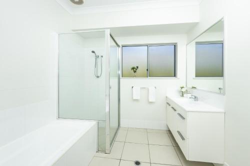 baño blanco con ducha y lavamanos en Cairns Beaches Home, Marina View, Sleeps 12 en Yorkeys Knob