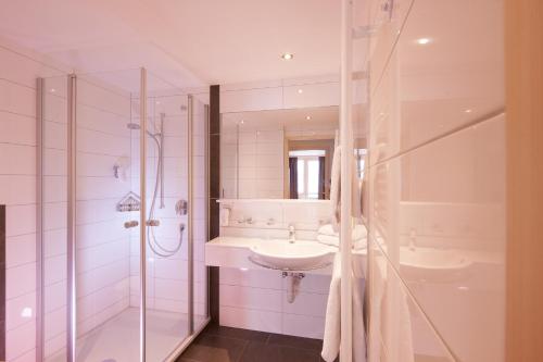 a white bathroom with a sink and a shower at Dorfgasthof Adler in Mellau