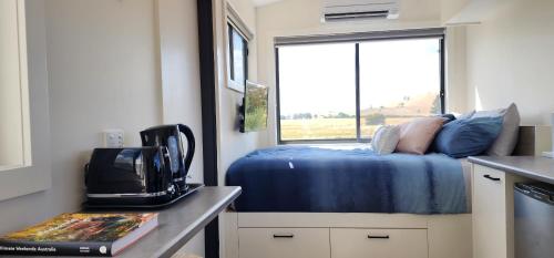 a small bedroom with a bed and a window at New Horizons Farm Stay in Smeaton