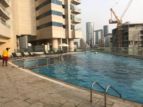 een man die naast een zwembad in een stad staat bij Large size one bedroom apartment with sea view in Abu Dhabi