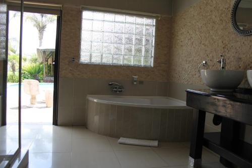 a bathroom with a tub and a sink and a window at Heimat Guesthouse in Welkom